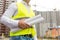 Closeup of engineer holding rolled blueprints in background of b