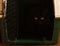 Closeup of the entrance of a pet carrier with a black cat hiding inside it in the darkness, almost invisible