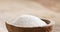 Closeup of extra sea salt in wood bowl on wooden table