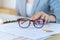 closeup eyeglasses and female hand on background laptop and grap