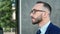 Closeup face of bearded man in glasses and tie going at office building. Shot with RED camera in 4K