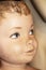 Closeup of face of cracked vintage little boy mannequin with foreground painted eye in focus