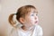 Closeup face portrait of funny two years old white girl on wall background