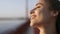 Closeup face of young pretty woman enjoying peaceful sunset and looking at sunset. Hair flowing in the wind. Calm and