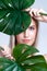 Closeup facial portrait personable woman holding green monstera.