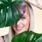 Closeup facial portrait personable woman holding green monstera.