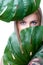 Closeup facial portrait personable woman holding green monstera.