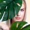 Closeup facial portrait personable woman holding green monstera.