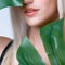 Closeup facial portrait personable woman holding green monstera.