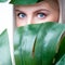 Closeup facial portrait personable woman holding green monstera.