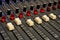 Closeup of faders on a large studio audio mixing board.