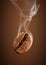 Closeup falling coffee bean with smoke on brown background