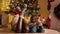 Closeup of family feet in knitted wool socks lying next to glowing Christmas tree in living room. Pure emotions of