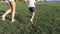 Closeup feet of mother and little daughter running on the green grass at park