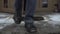 Closeup feet on the snow covered stairs and porch. Man opens the door of a building and goes outside to the city street