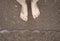 Closeup feet of young woman standing on sea shore;  sea wave reaching the feet. Summer activity.