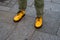 Closeup of feet of young woman wearing yellow dc martens shoes in the street