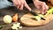 Closeup of female chef hands slicing peeled Celery on a wooden cutting board next to sliced vegetables. The concept of