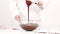 Closeup female chef mixing dark melted chocolate in glass bowl, slow motion