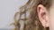 Closeup female ear with earrings front view. Right ear of curly young woman on gray background. Human hearing organs