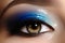 Closeup female eye with beautiful fashion bright make-up. Beautiful shiny blue eyeshadow, wet glitter, black eyeliner