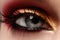 Closeup female eye with fashion bright make-up. Beautiful shiny gold, pink eyeshadow, wet glitter, black eyeliner
