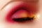 Closeup female eye with fashion bright make-up. Beautiful shiny gold, pink eyeshadow, wet glitter, black eyeliner