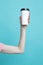 Closeup of Female Girl Hand Pointing with Finger Cup of Coffee Drink Isolated on Vivid Trendy Turquoise background