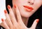 Closeup female hand with beautiful orange nails at woman\'s face