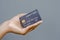 Closeup female hand holding a black credit card mockup with security chip embedded on a gray background