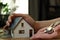 Closeup of a female hand holding keys next to the miniature house - Real estate concept