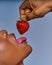 Closeup female hand holds vivid ripe red strawberry at the mouth. Diet concept