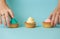 Closeup of female hands choosing between three colorful cupcakes