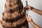 Closeup of female hands of hairdresser or coiffeur makes hairstyle. Hair