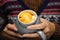 Closeup of female hands with a mug of creative beverage of mandarin orange lobule. Young hipster woman in Christmas