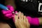 Closeup of female hands in pink gloves remove the gel varnish coatings with a professional apparatus