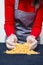 Closeup of Female Hands Pouring Out Wax Depilation Granules On Blue Textile Background