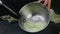 Closeup female hands whisking egg whites by whisk in deep metal bowl