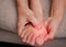 Closeup of female holding her painful feet and massaging her bunion toes to relieve pain. Swollen bunion at the edge of the big