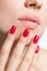 Closeup of female lips and hand with red nail polish.