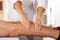 Closeup female physio therapist hands working on male patients legs, blurry clinic background