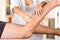 Closeup female physio therapist hands working on male patients legs, blurry clinic background