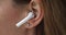 Closeup female put on white modern wireless earphone in ear