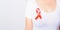 Closeup of female with red ribbon Support HIV AIDS on shirt