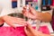 Closeup females hands getting manicure treatment from woman applying transparent liquid in salon environment, pink towel