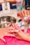 Closeup females hands getting manicure treatment from woman applying transparent liquid in salon environment, pink towel