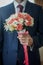 Closeup of a fiance in suit with wedding flowers