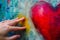 closeup of fingers smudging edges of a painted heart on canvas