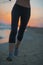 Closeup on fitness woman running on beach at dusk