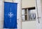 Closeup of the flag of NATO hanging from a building under the sunlight